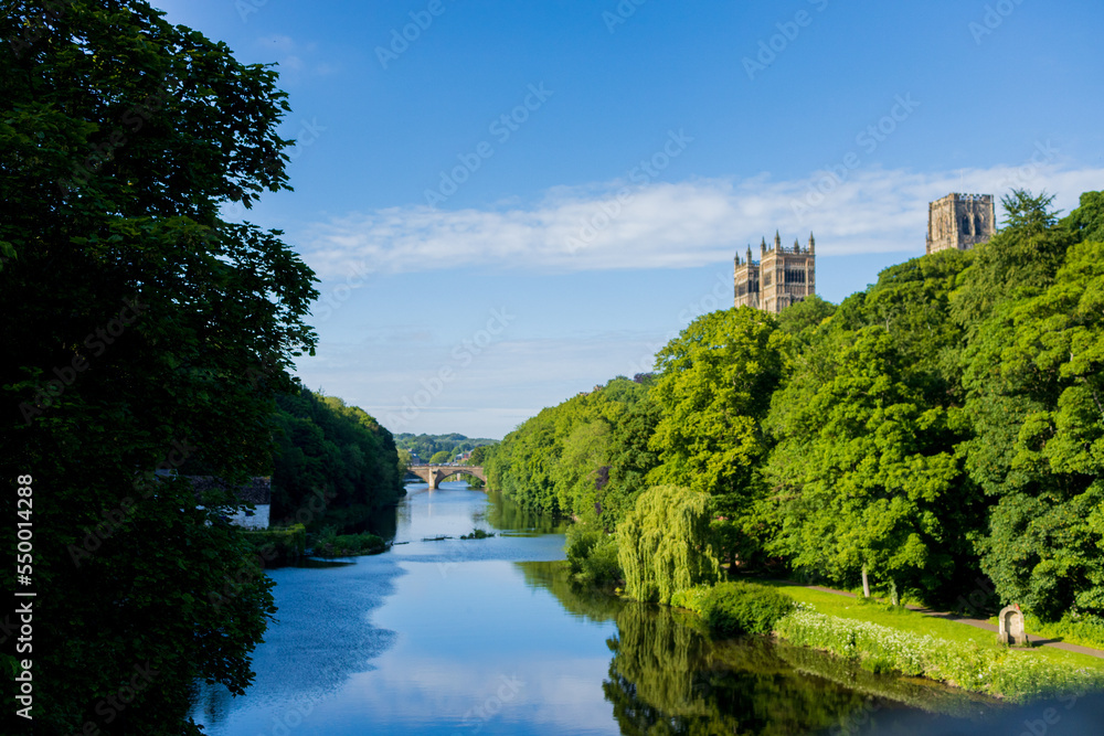 Durham England: 2022-06-07: Durham Cathedral exterior during sunny summer day. View from river wear with lush green trees