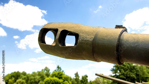 Fotografie The muzzle of a cannon of a military tank against the blue sky, close-up