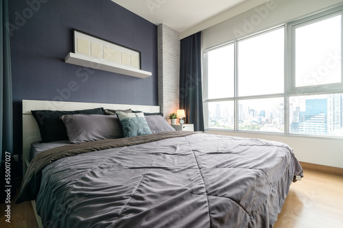 Warm and cozy interior of bedding room space with bed, mock up poster frame. Cozy home decor.