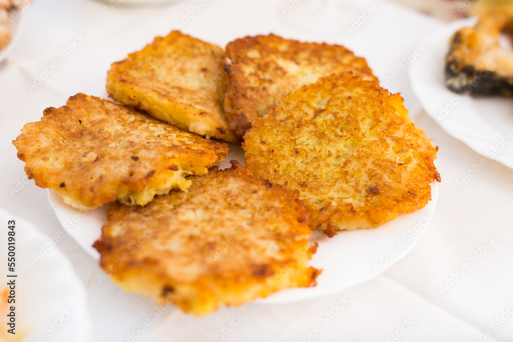 Fried grated potato pancakes with sour cream on white plate Fried grated potato pancakes with sour cream on white plate