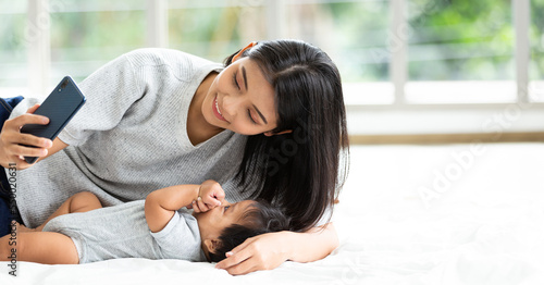 Portrait happy young asian mother taking selfie with little baby son in the living room. Family, technology, parenthood and people concept.