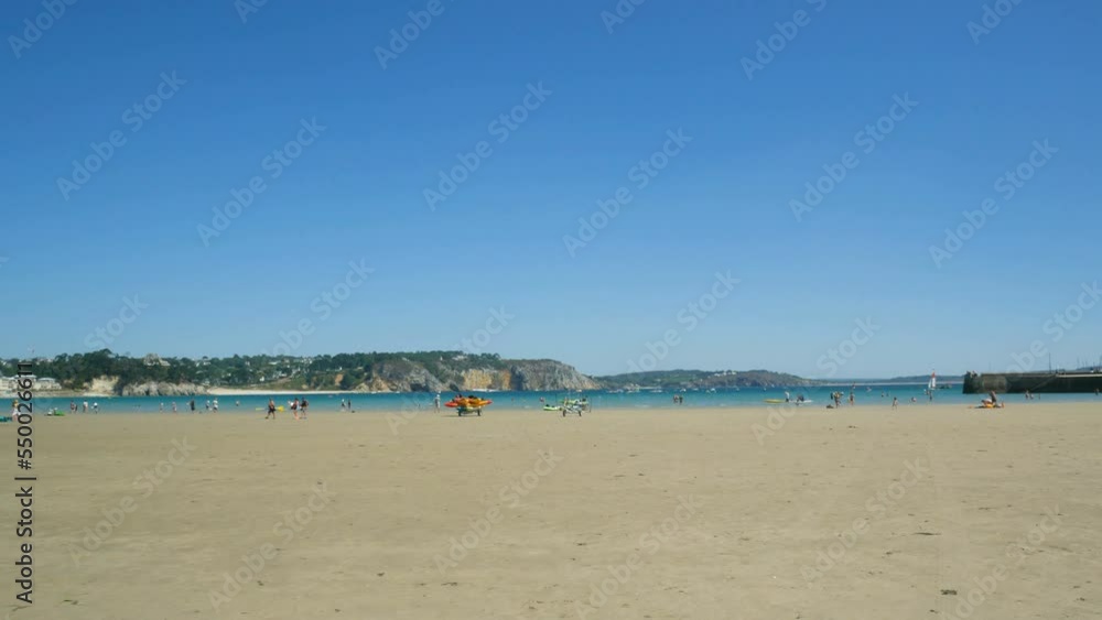 The beach of Morgat, Brittany, France, on the Atlantic ocean during low tide. In the foreground wet sand. On the background blue waters and tourists. The beach of Morgat, Brittany, France, on the Atlantic ocean during low tide. In the foreground wet sand. On the background blue waters and tourists.