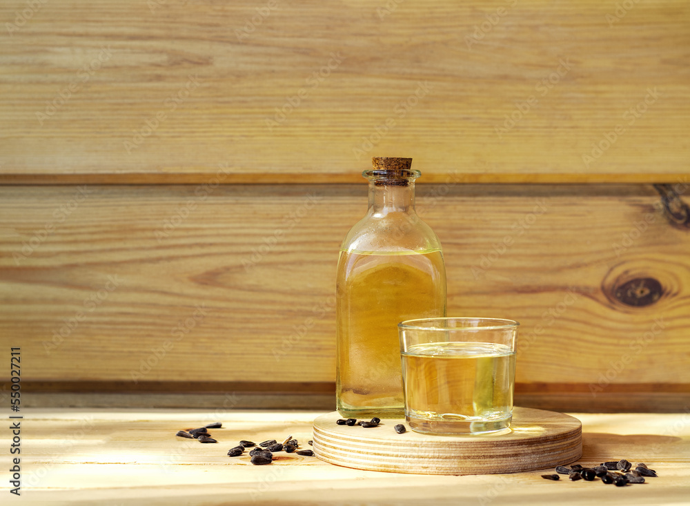 Sunflower oil in a bottle glass with seeds on wooden background Sunflower oil in a bottle glass with seeds on wooden background