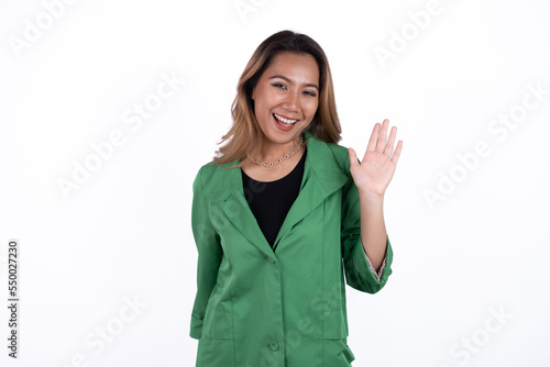 Friendly business woman, asian office lady waving hand and saying hello, hi gesture, standing over white background © Parichat