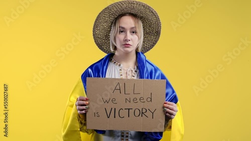 Ukrainian woman with cardboard All we need is victory on yellow background. Ukraine will win war. Democracy, liberty, demonstration, russian aggresion concept photo