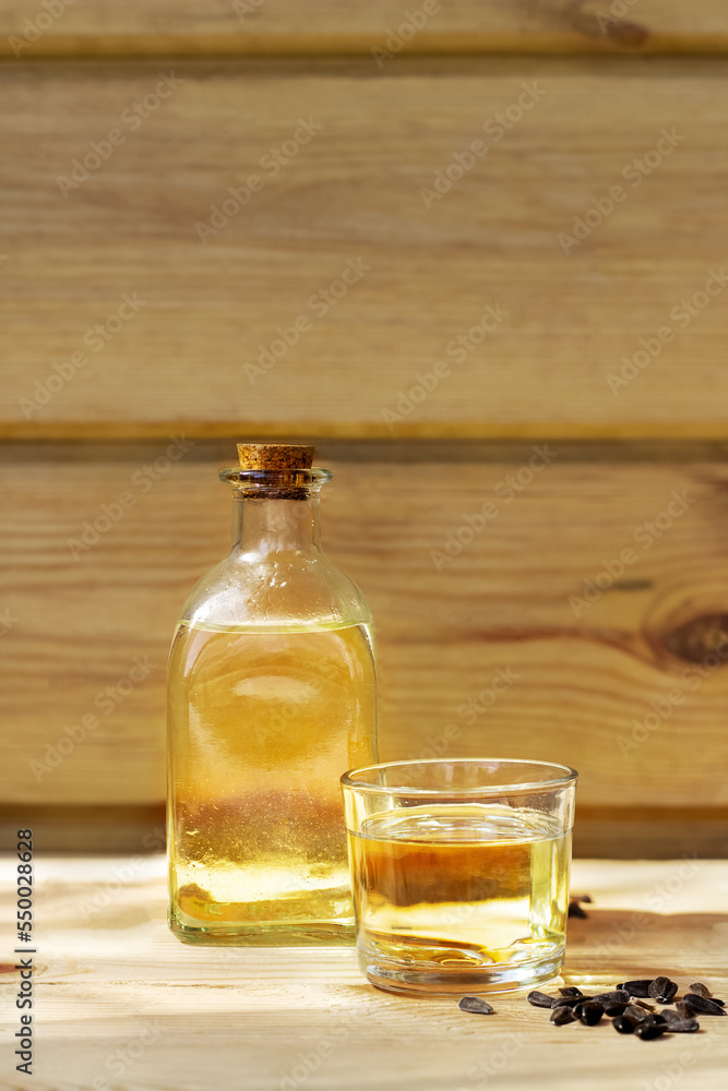 Sunflower oil in a bottle glass with seeds on the wooden background Sunflower oil in a bottle glass with seeds on the wooden background