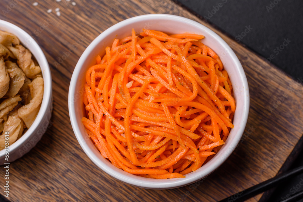 Tasty spicy Korean carrot with spices and herbs on a dark concrete background