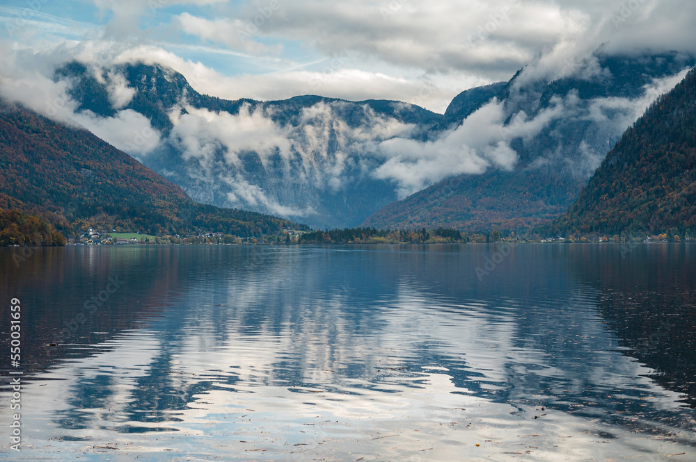 Panorama view of Hallstattersee mountain in daylight with snow and cloudy sky