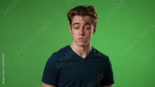 Pointing fingers himself ask say who me waving and smiling, confused young man 20s posing isolated on green screen background in studio. People lifestyle concept. Slow motion photo