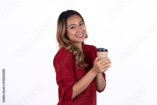 Happy young energetic asian woman smiling, drinking, holding cup mug of coffee, standing confident against white background
