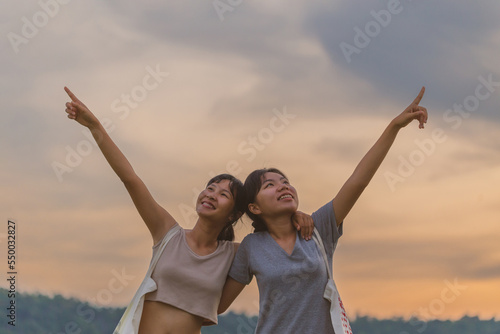 Young women are having fun on the green field in the evening. Women enjoying nature. Carefree Happy Women. Freedom concept. beautiful girls LGBT lesbian girlfriend outdoors in the evening.