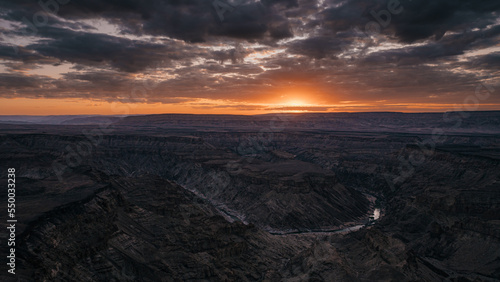 Dramatischer Sonnenuntergang - Blick auf eine Schleife des Fish Rivers bei Sonnenuntergang, wie er sich durch den Fish River Canyon windet (Namibia)