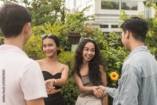 4 young people meet each other during a blind double date. Introducing oneself with a handshake. First time meeting after connecting via a dating app.