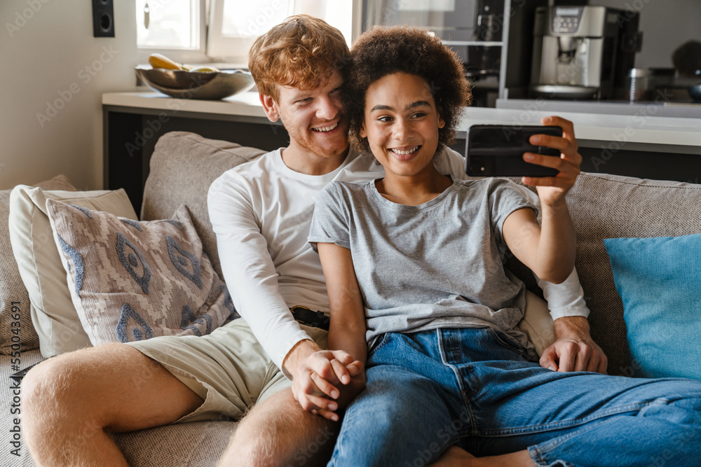 Young happy interracial couple taking selfie with phone together Young happy interracial couple taking selfie with phone together
