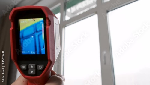 Inspection of a window block inside the room with a thermal imager, searching for heat loss in a building. Thermography concept