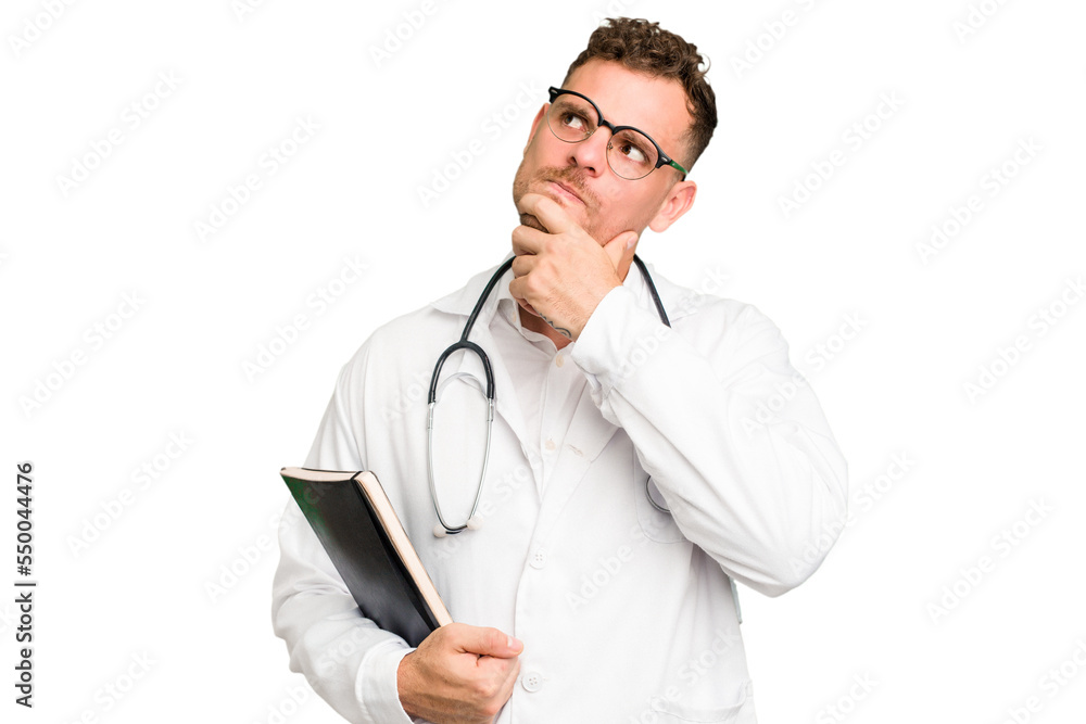 Young doctor caucasian man holding a book isolated looking sideways with doubtful and skeptical expression. Young doctor caucasian man holding a book isolated looking sideways with doubtful and skeptical expression.
