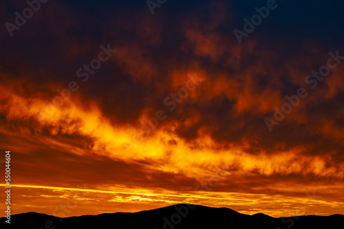 The beautiful colors of the clouds during sunrise over hills in silhouette