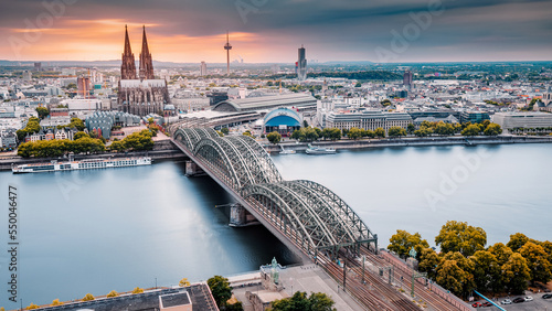 Фотография Cologne Aerial view with trains move on a bridge over the Rhine River on which cargo barges and passenger ships ply