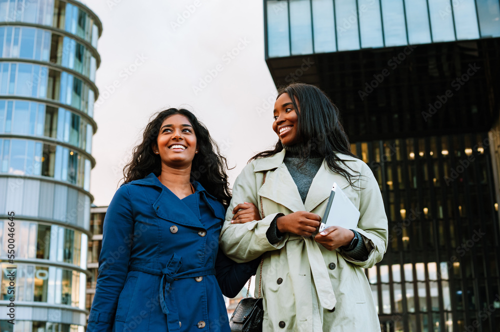 Two young joyful women walking outdoors at the city street Two young joyful women walking outdoors at the city street