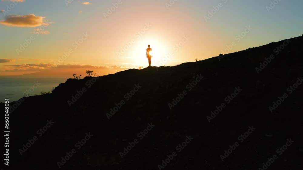 Girl silhouette illuminated by sun rays with dark natural landscape mountain cliffs on sunset glare background. Aerial colorful sky. Beauty of nature. Los Gigantes Tenerife. Girl silhouette illuminated by sun rays with dark natural landscape mountain cliffs on sunset glare background. Aerial colorful sky. Beauty of nature. Los Gigantes Tenerife.