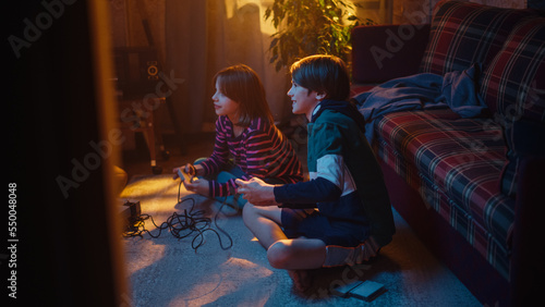 Nostalgic Childhood Concept. Young Brother and Sister Playing Old-School Arcade Video Game on a Retro TV Set in a Living Room with Period-Correct Interior. Friends Spend the Day at Home Playing Games.