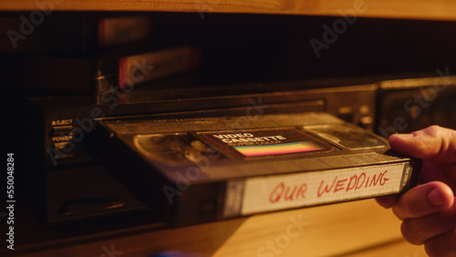 Quadro su tela Close Up of a Person Inserting a VHS Cassette in a Player with Nostalgic Wedding Footage from Home Video Camera
