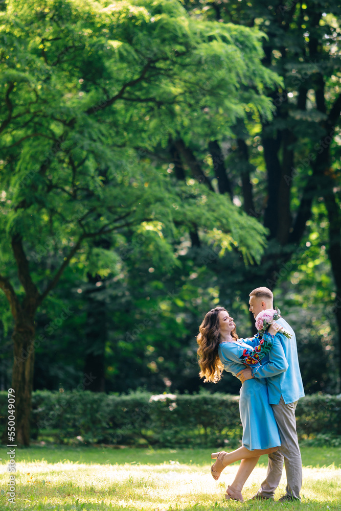 Stylish couple of happy newlyweds walking in the park on the wedding day with a bouquet. The couple will happily spend time together Stylish couple of happy newlyweds walking in the park on the wedding day with a bouquet. The couple will happily spend time together