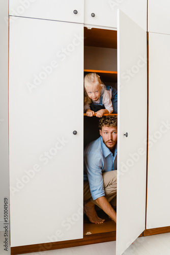 Young white father and his little daughter having fun in closet at home