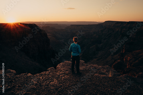 Frau blickt bei Sonnenuntergang in den Fish River Canyon, Namibia