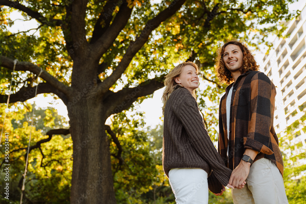 Young loving couple smiling and holding hands outdoors in park Young loving couple smiling and holding hands outdoors in park