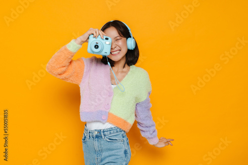 Asian young woman in headphones taking photo on instant camera