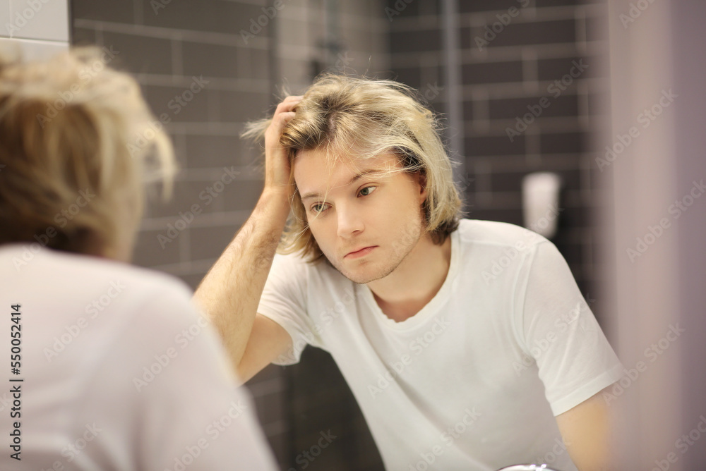 young man looking in the mirror,combing his hair,looking at problems on face. young man looking in the mirror,combing his hair,looking at problems on face.