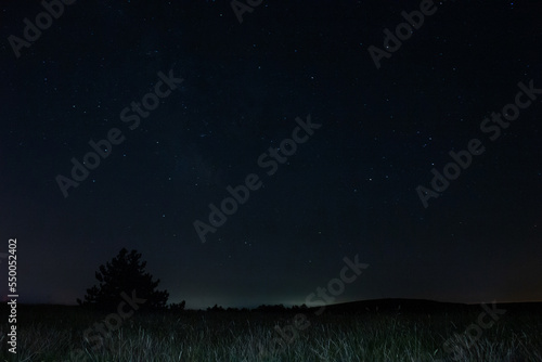 Milky Way stars with countryside landscape.