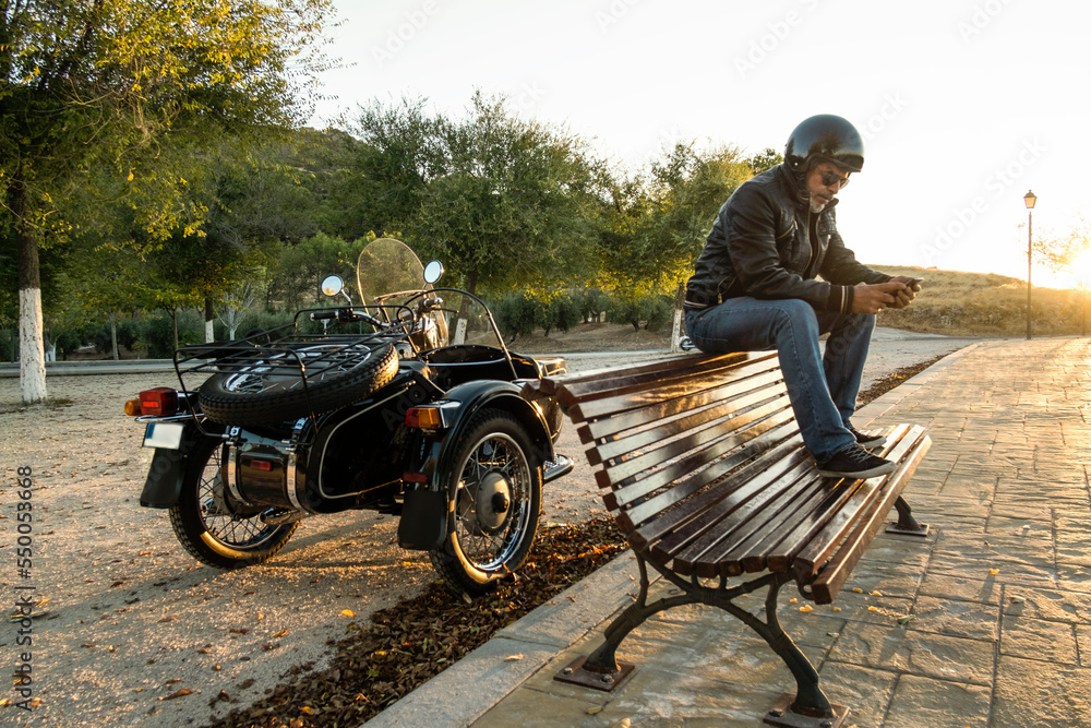 Mature man in sidecar sends an SMS message on his mobile Mature man in sidecar sends an SMS message on his mobile