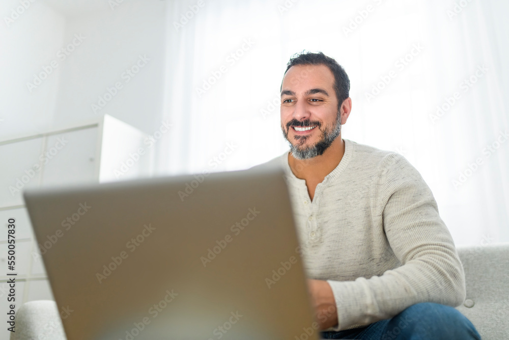 man with black hair using laptop at home sofa man with black hair using laptop at home sofa