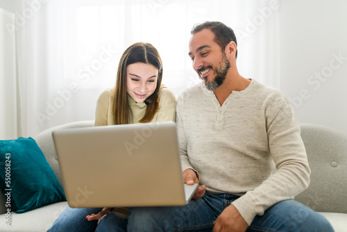 father with teen child daughter having fun using laptop computer at home