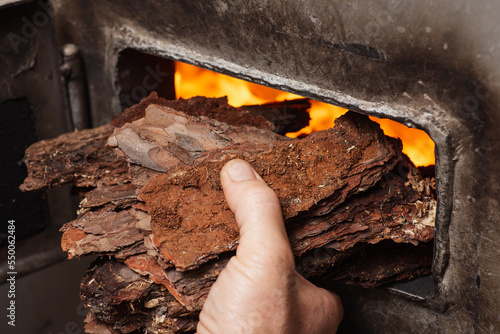 Photos Man stoker puts bark in boiler to keep the fire burning
