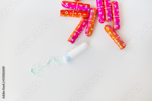 Medical female tampon in pink and orange packaging on a white background. Hygienic white tampon for women. Cotton swab. Menstruation, contraception. photo