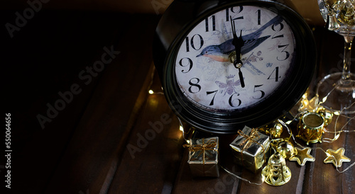 new year eve concept background with old decorated clock, lights and decoration on wooden table.