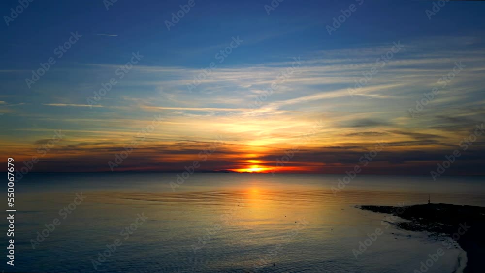 Aerial view of a rocky bay in silhouette being flown over by a drone at sunset Aerial view of a rocky bay in silhouette being flown over by a drone at sunset