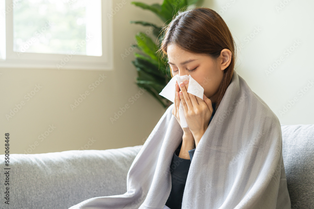 Sick, coronavirus or covid-19, attractive asian young woman, girl have a fever, flu and hand in use tissues paper sneezing nose, runny while sitting on sofa, couch at home. Health care on virus person Sick, coronavirus or covid-19, attractive asian young woman, girl have a fever, flu and hand in use tissues paper sneezing nose, runny while sitting on sofa, couch at home. Health care on virus person