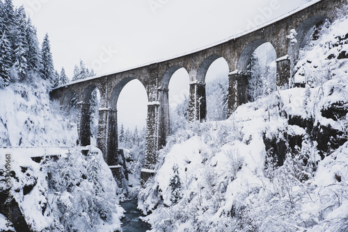 Mountain landscape with Sainte Marie bridge covered with snow in Les Houches, Chamonix valley, Eastern France. Viaduct bridge built to carry a railway over water.