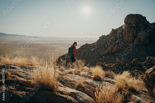 Ein Mädchen wandert kurz vor Sonnenuntergang über einen Grat am Rande der Aus-Berge - im Hintergrund die Weite der Namib (Klein-Aus Vista, Namibia)