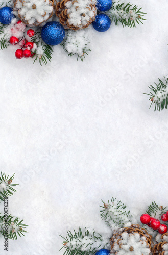 Christmas decoration. Cone pine, branches christmas tree, blue ball, red berries on snow with space for text. Top view, flat lay