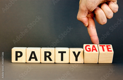 Party and partygate symbol. Concept words Party and Partygate on wooden cubes. Businessman hand. Beautiful grey table grey background. Business party and partygate concept. Copy space.