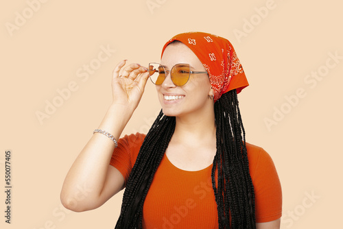 Smiling woman with box braids wears her orange glasses while looking far. photo