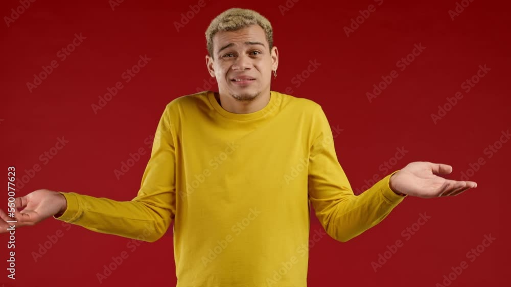 Confused young man, shoulders up - can't help, makes gesture of I dont know. Difficult question, guilty reaction, puzzled stylish guy on red background. Confused young man, shoulders up - can't help, makes gesture of I dont know. Difficult question, guilty reaction, puzzled stylish guy on red background.