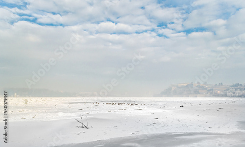 The bank of the Danube river covered with snow. Danube River covered with snow and ice. Frozen and snow-covered waterway of Danube river below Petrovaradin fortress, Vojvodina, Novi Sad, Petrovaradin,