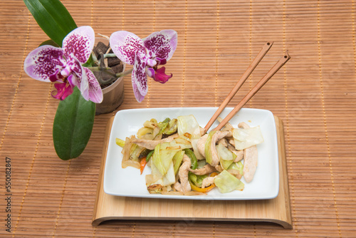 mushroom dish with vegetables on a table with bamboo tablecloth and orchid photo