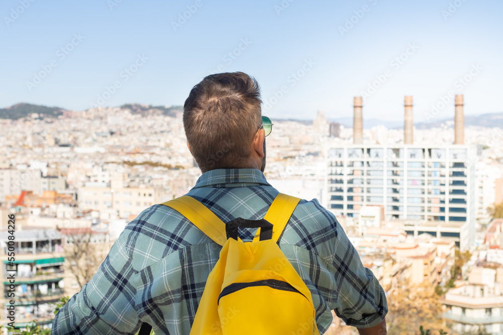 Close-up portrait of an unrecognizable man with a yellow backpack on a viewpoint in Barcelona (Spain).